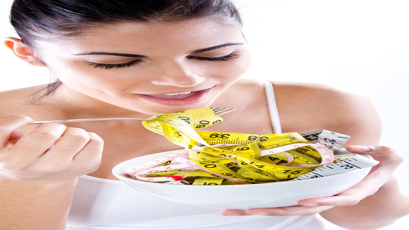 Mulher se alimentando com fita métrica, simbolizando o conceito de emagrecimento saudável